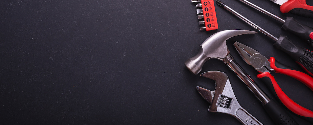 A hammer, wrench, pliers, and other tools atop a black granite surface