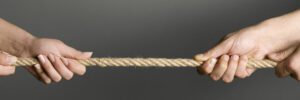 Two sets of hands pulling in opposite directions on a taut rope as if playing tug-of-war