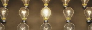 An array of lit lightbulbs arranged in three rows with the bulb in the center shining brightest