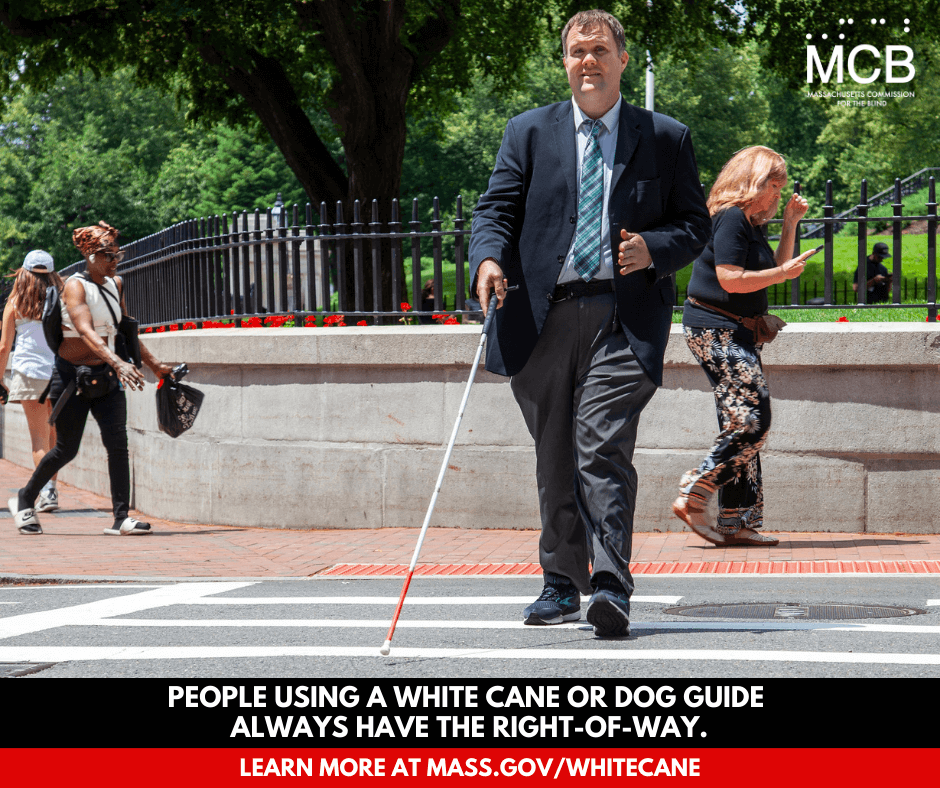 A man uses a white cane while crossing a city street; a caption reads 'People using a white cane or dog guide always have the right-of-way - learn more at mass.gov/whitecane'