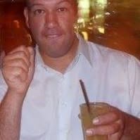A grinning Matthew grinning while wearing a white t-shirt and holding a pencil