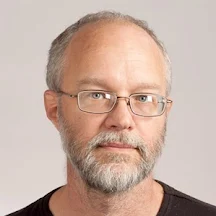 Headshot of Brian Johnson, a white man with greying hair, mustache, and beard wearing a black shirt.